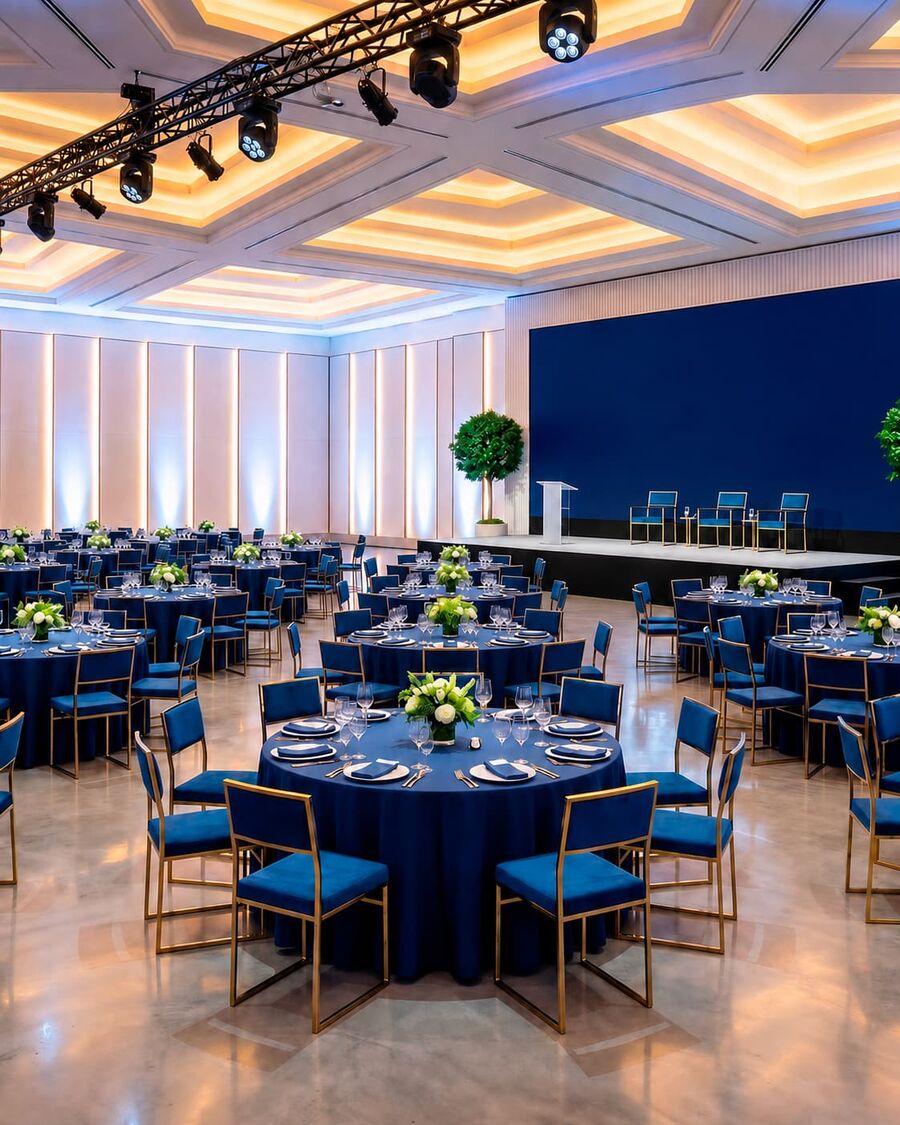 Salón corporativo con mesas, escenario y pantalla
